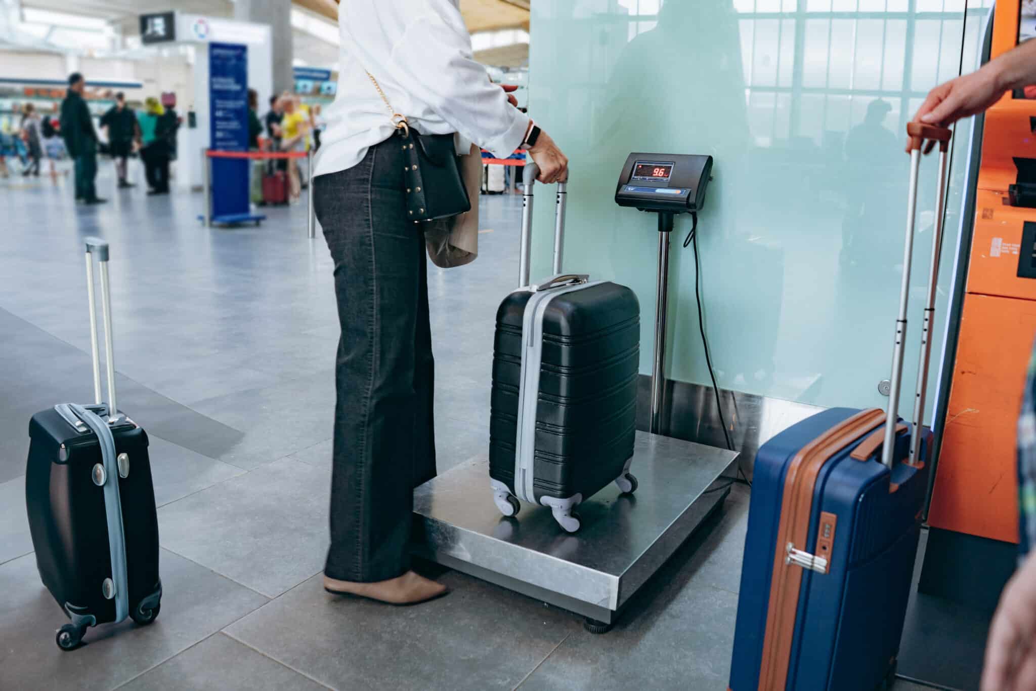 mujer elegante que pone la maleta sobre las pesas en el aeropuerto midiendo el equipaje